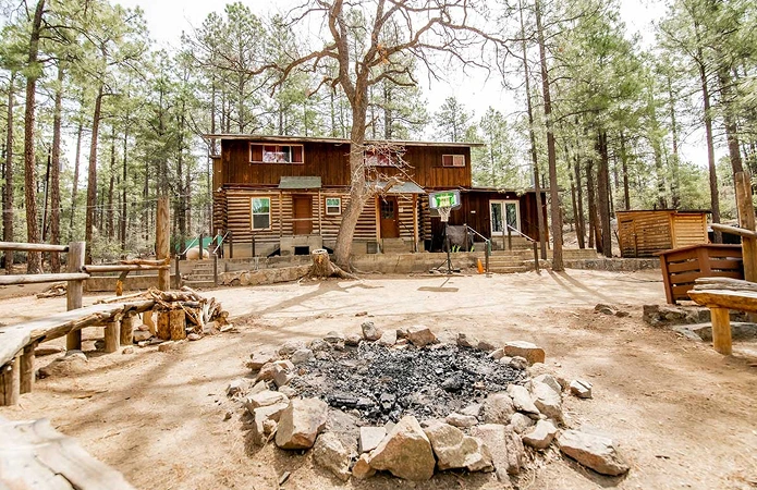 A log cabin among the pines at Camp Way, with a fire pit out front